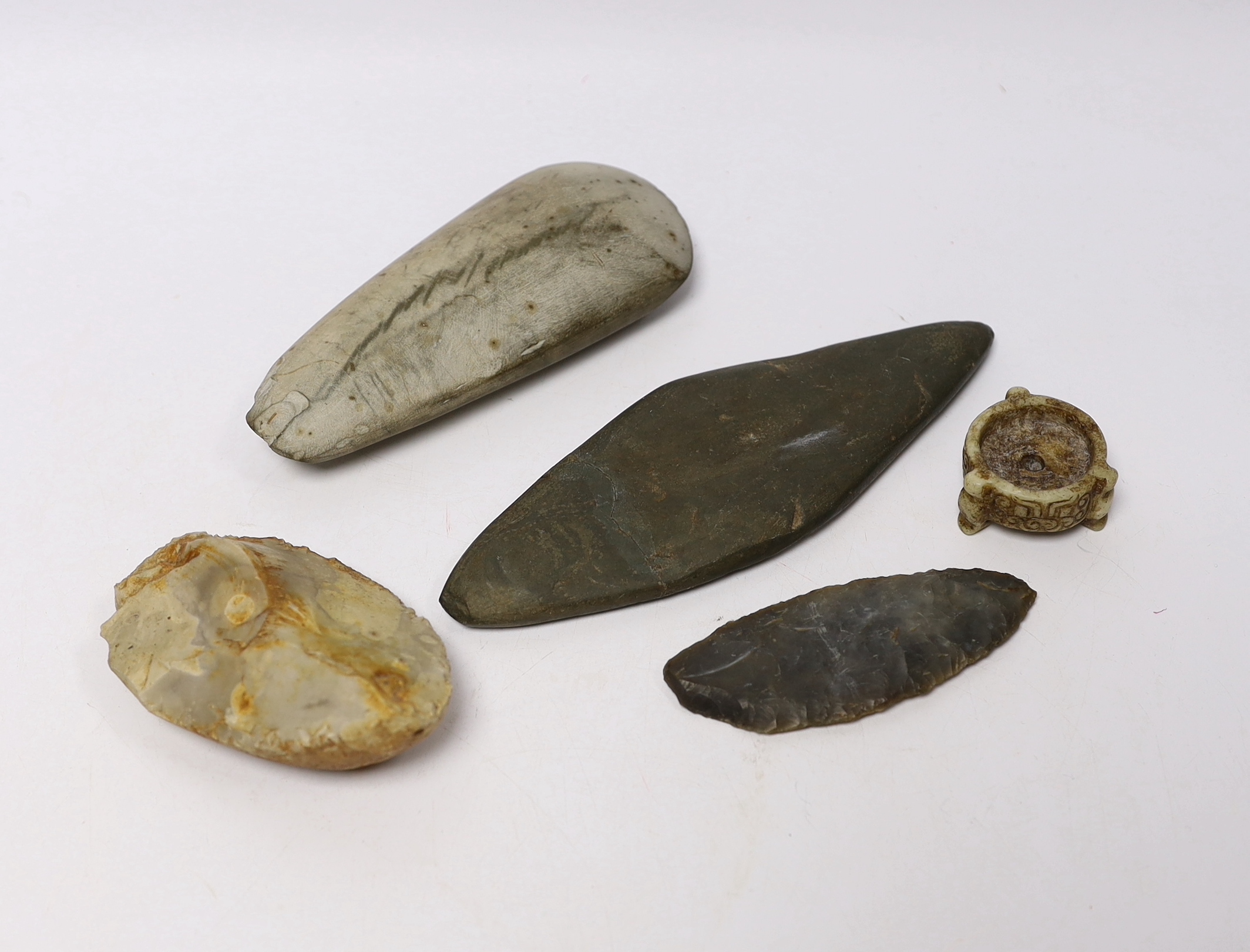 A collection of stone handtools and a Chinese hardstone carving, largest 19cm in length